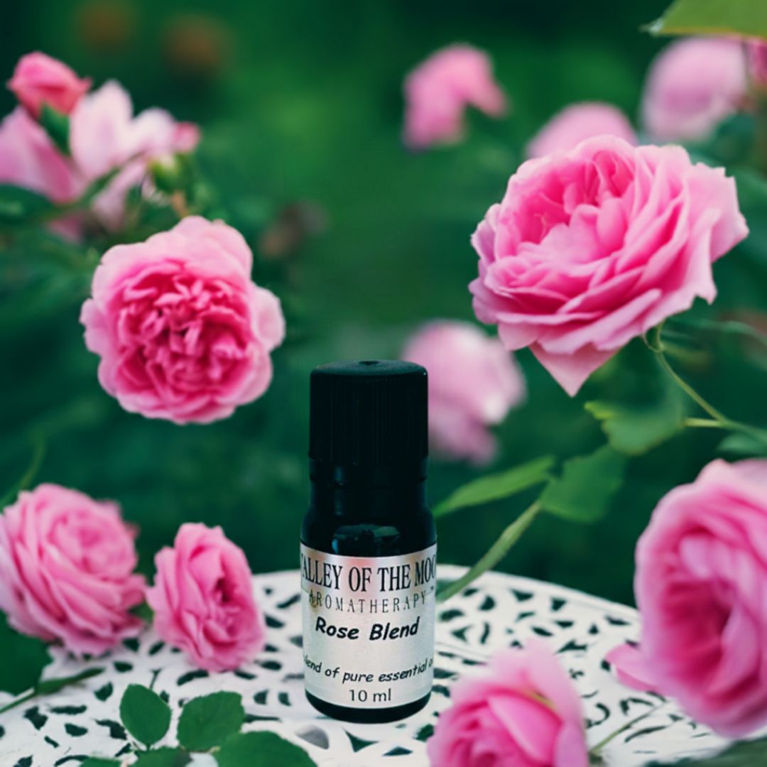 Rose Essential Oil Blend on a white table with rose pink flowers