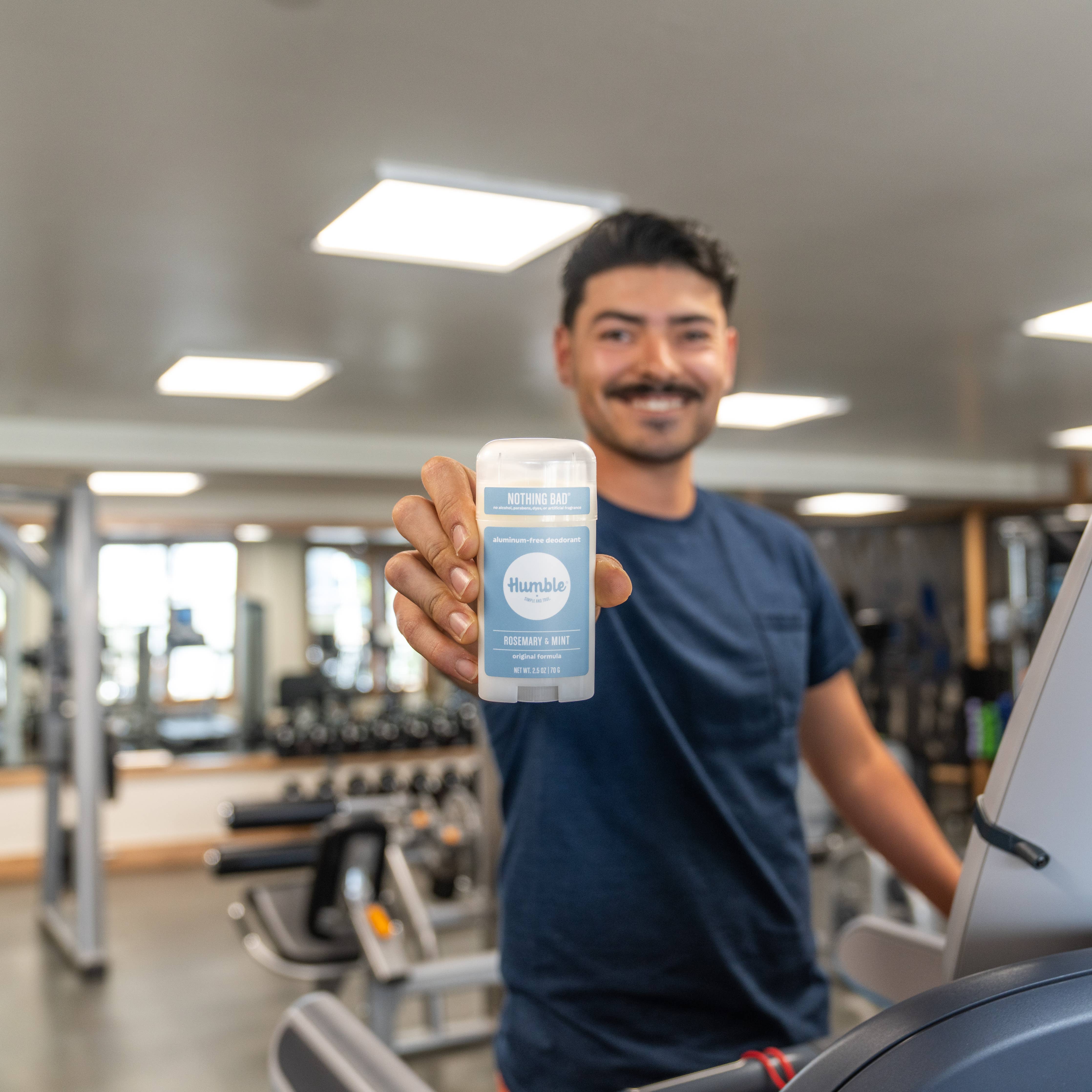 Man in a gym holding Humble original formula deodorant – Rosemary & Mint scent, aluminum free www.aromathyme.com