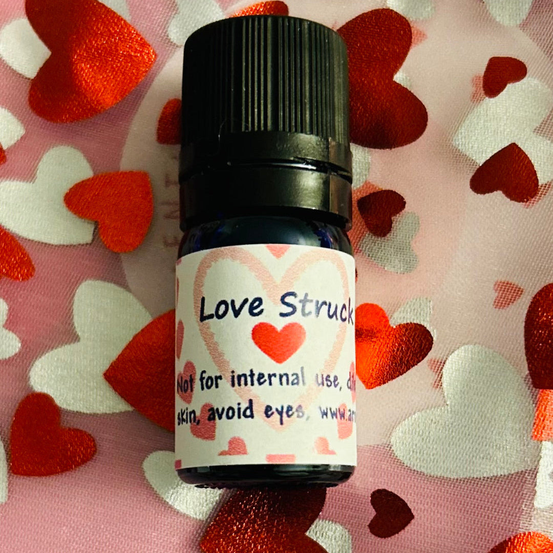 A small bottle labeled 'Love Struck' essential oil blend, with a background of red and white hearts.