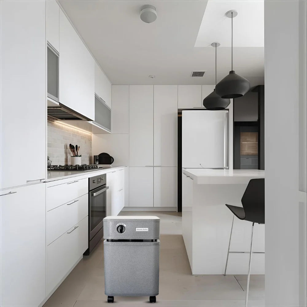 Modern kitchen with white cabinets, stainless steel appliances, and a small gray robot vacuum cleaner.