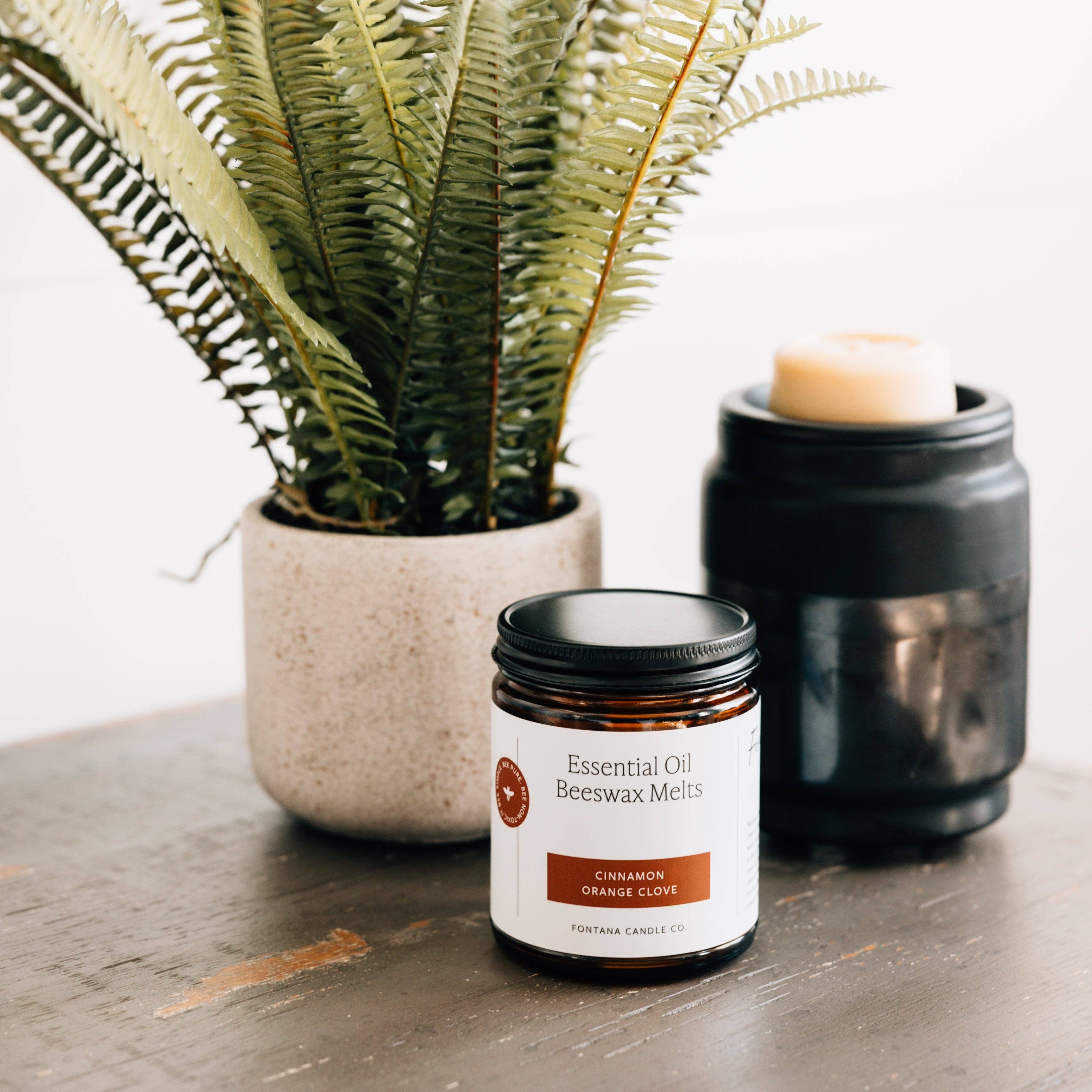 Essential oil beewax melts jar with a candle and plant on a wooden surface