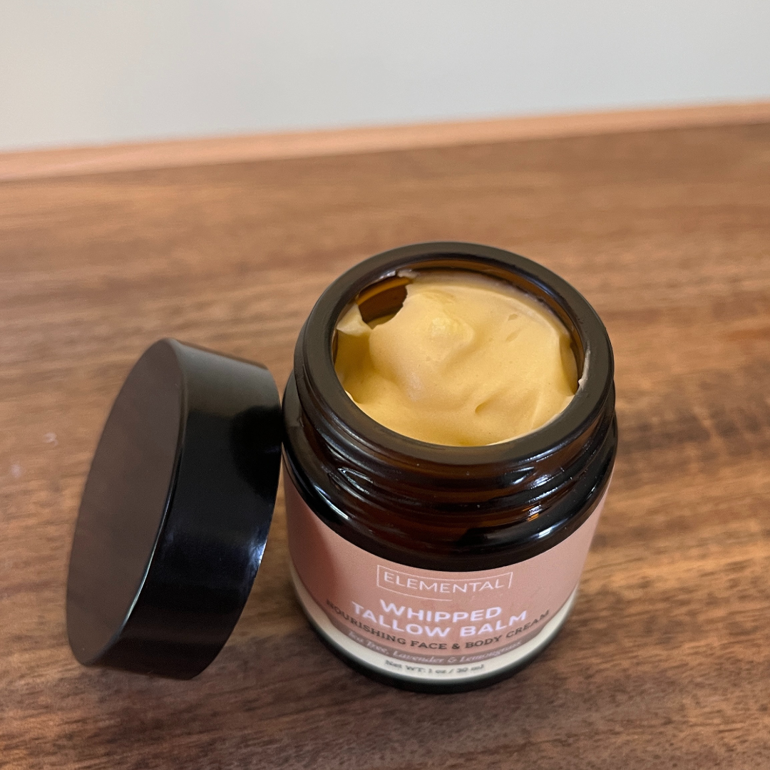 Open jar of Elemental Whipped Tallow Balm on a wooden surface