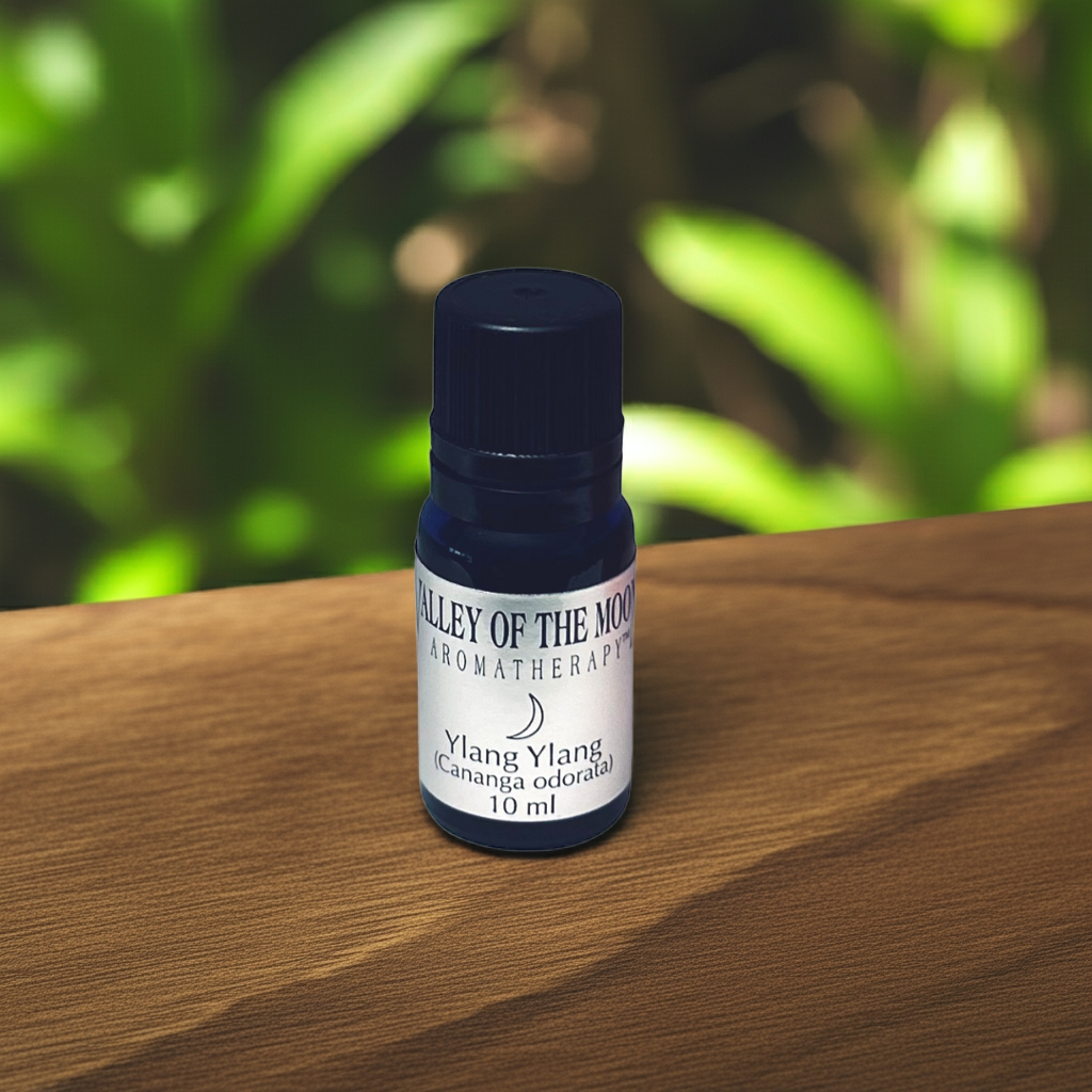 Bottle of Valley of the Moon Aromatherapy Ylang Ylang oil on a wooden surface with a blurred green background